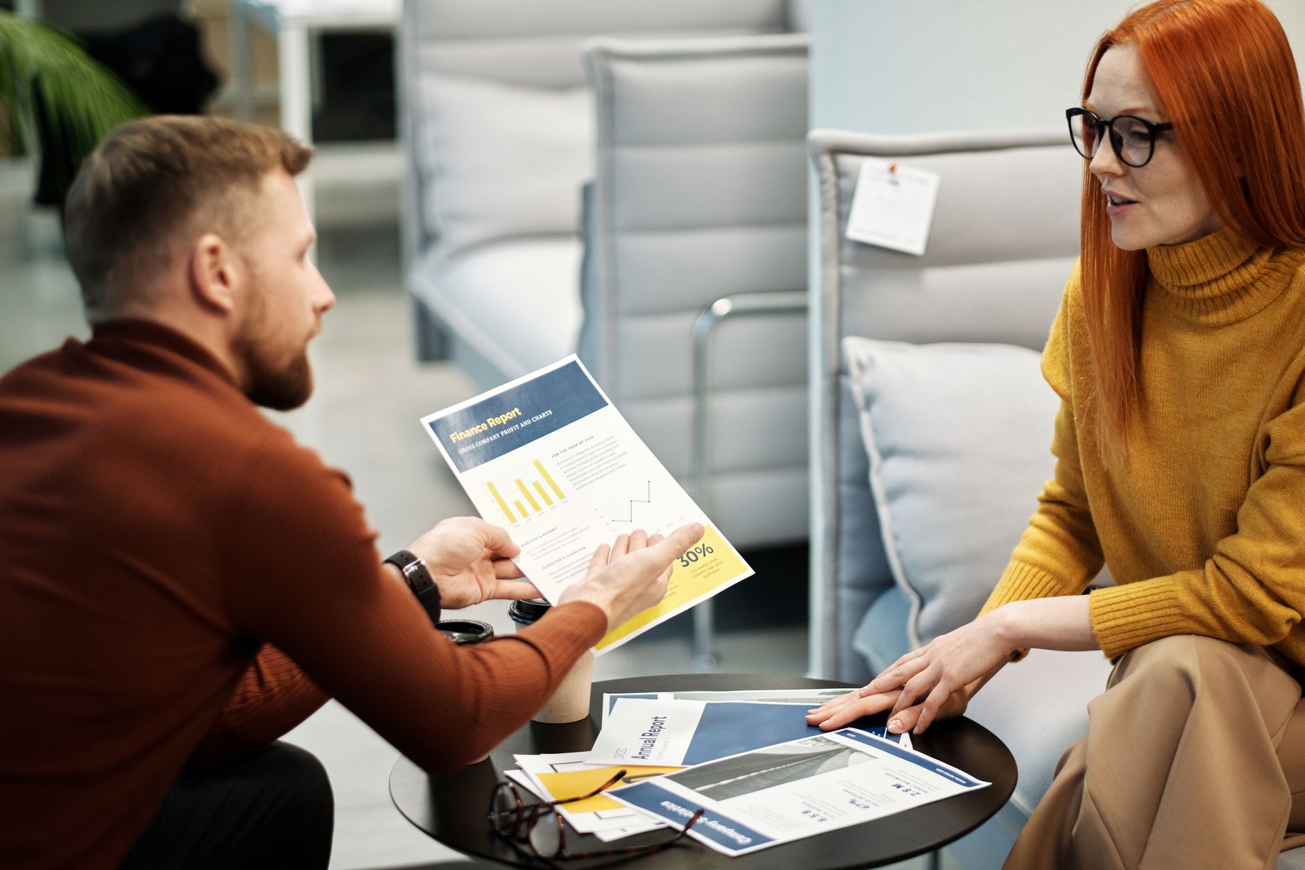 Colleagues reviewing a printed sustainability report at a desk in a bright office